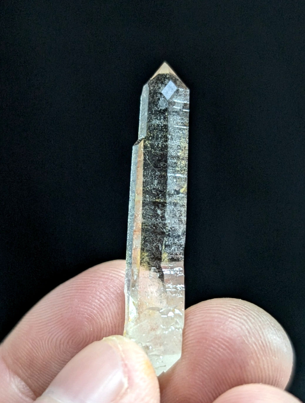 A translucent, clear quartz crystal with a pointed tip and visible internal inclusions.