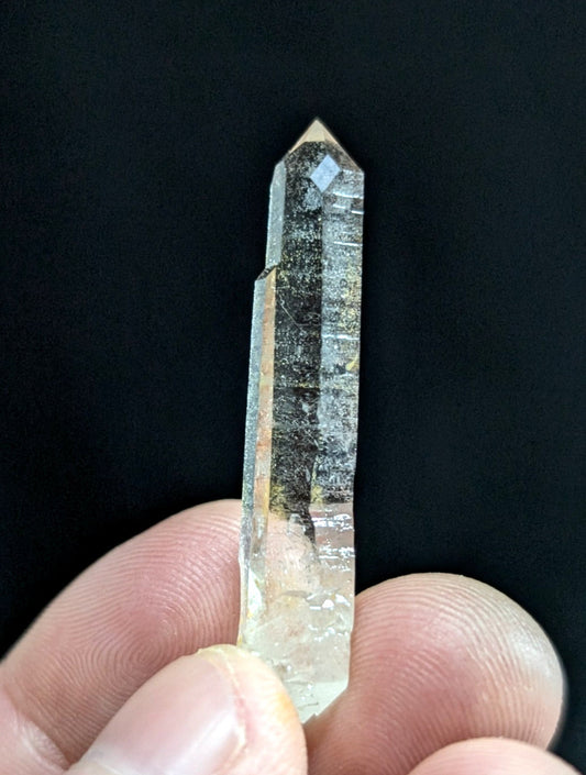 A translucent, clear quartz crystal with a pointed tip and visible internal inclusions.