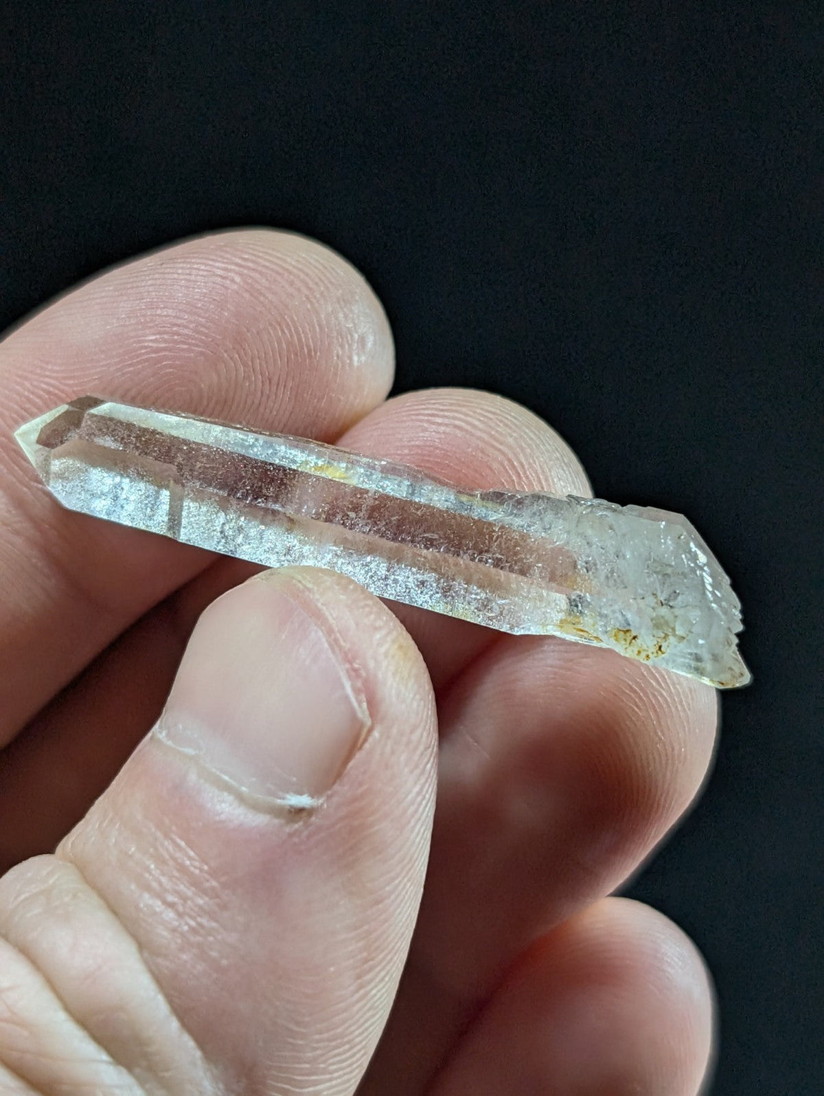 A translucent, clear quartz crystal with a pointed tip and natural striations.