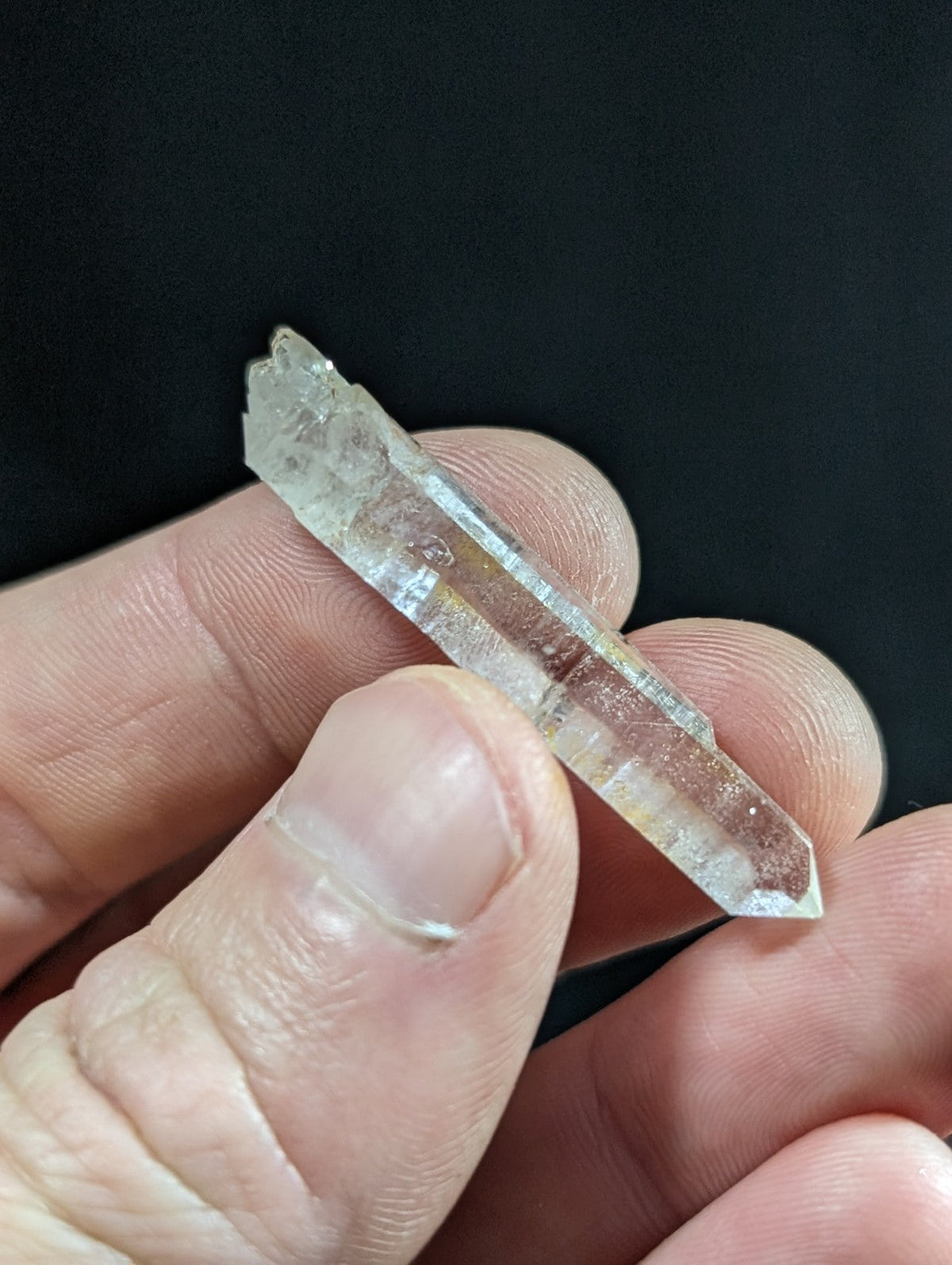 A clear, translucent quartz crystal with a pointed tip and natural facets.
