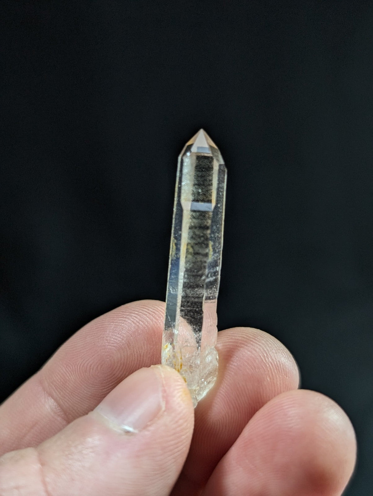 A translucent, clear quartz crystal with a pointed tip and visible internal inclusions.