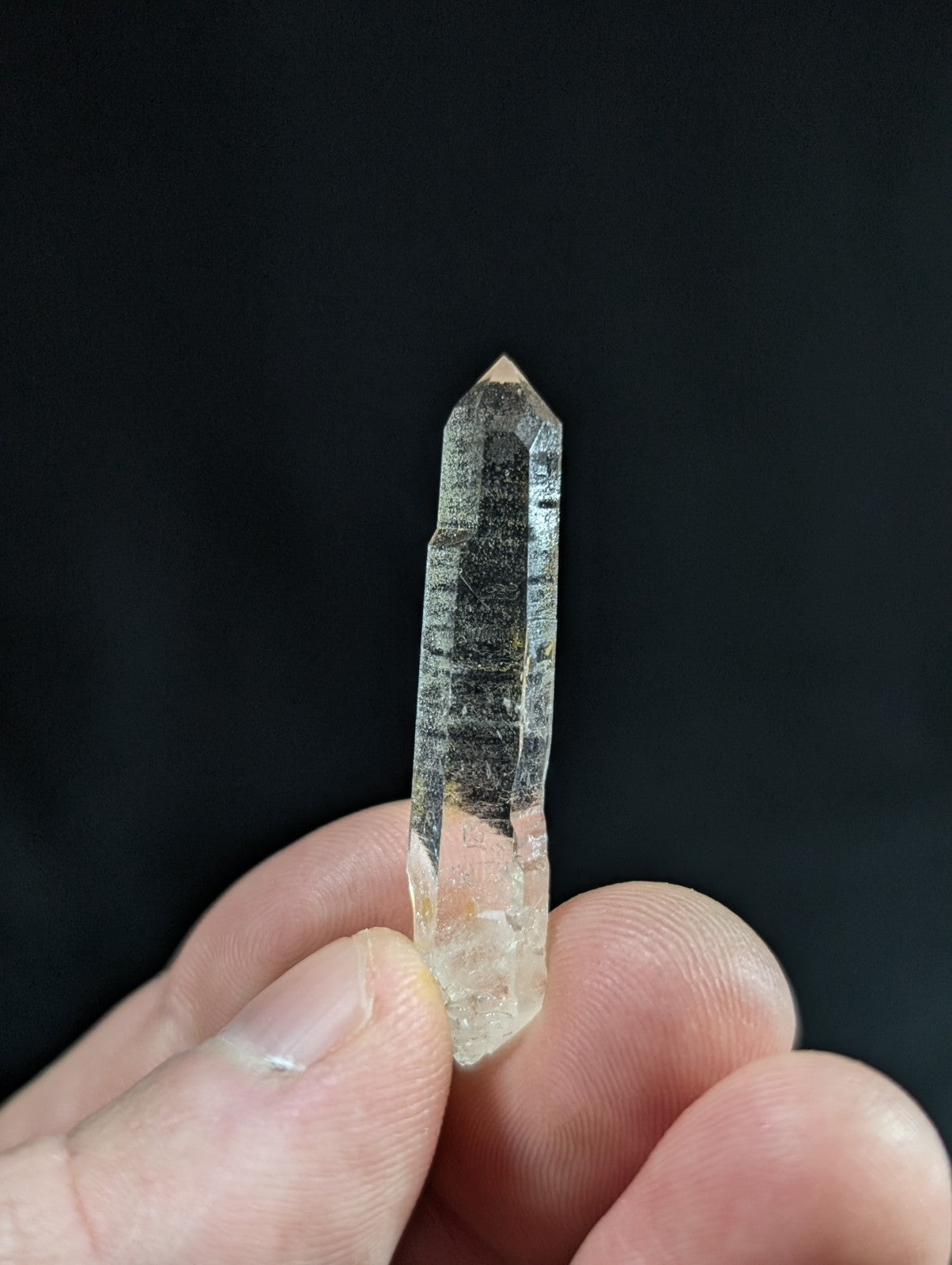 A translucent, clear quartz crystal with a pointed tip and visible internal striations.
