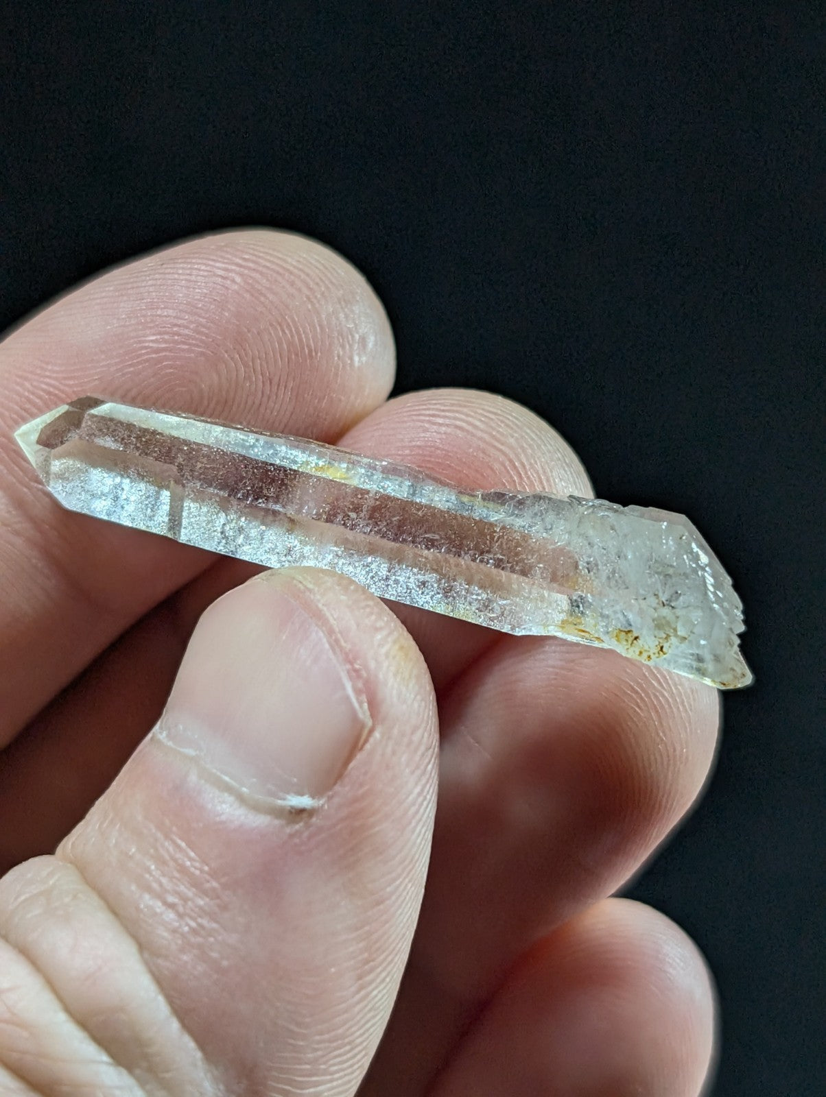 A translucent, clear quartz crystal with a pointed tip and natural striations.