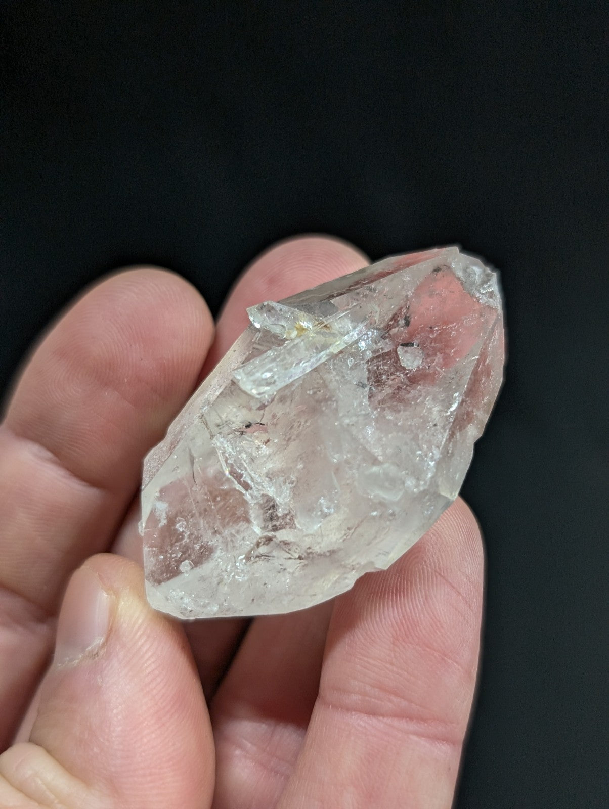 A clear, faceted quartz crystal with natural inclusions and a pointed tip.