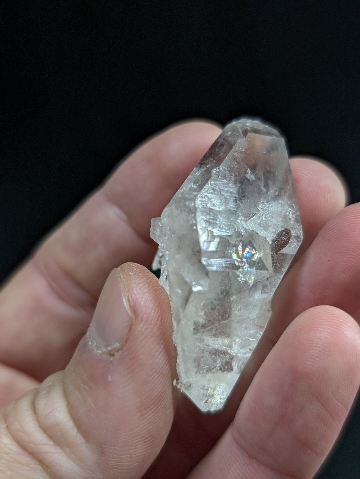 A clear, faceted quartz crystal with natural inclusions and a pointed tip.