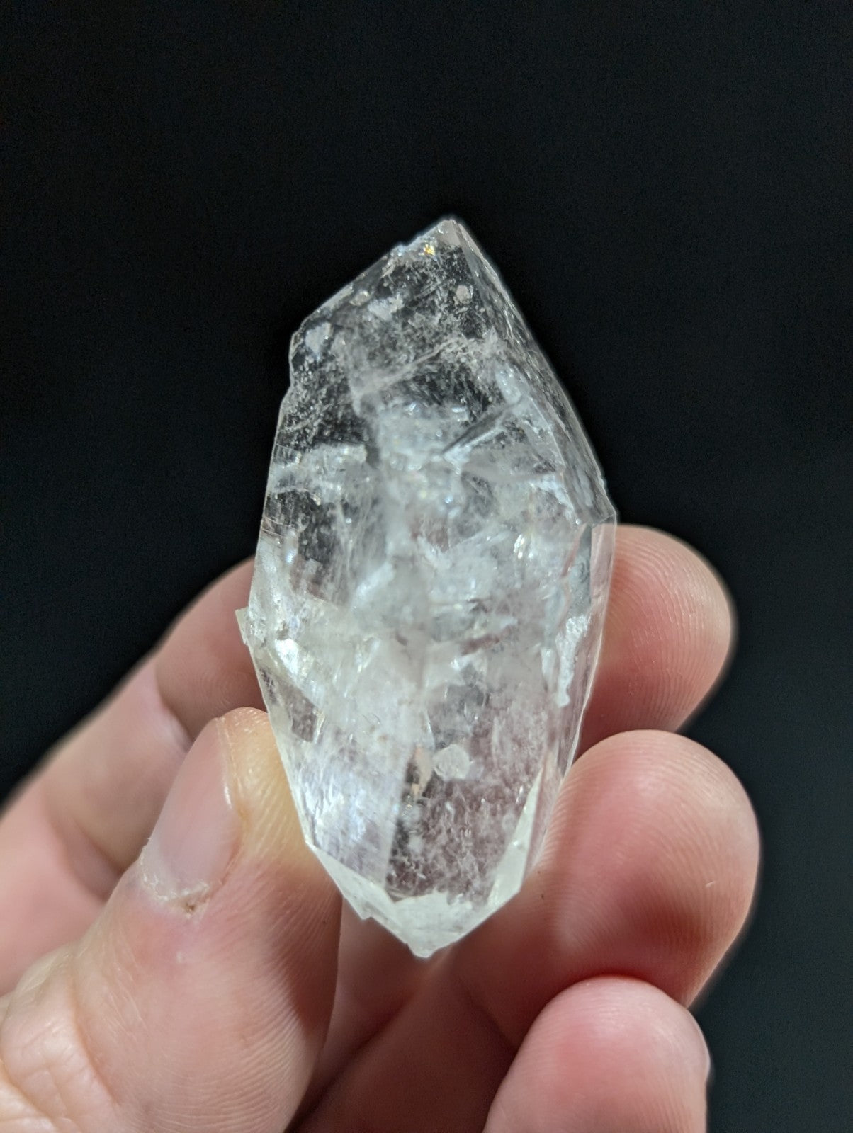 A clear, faceted quartz crystal with a pointed tip and natural internal inclusions.