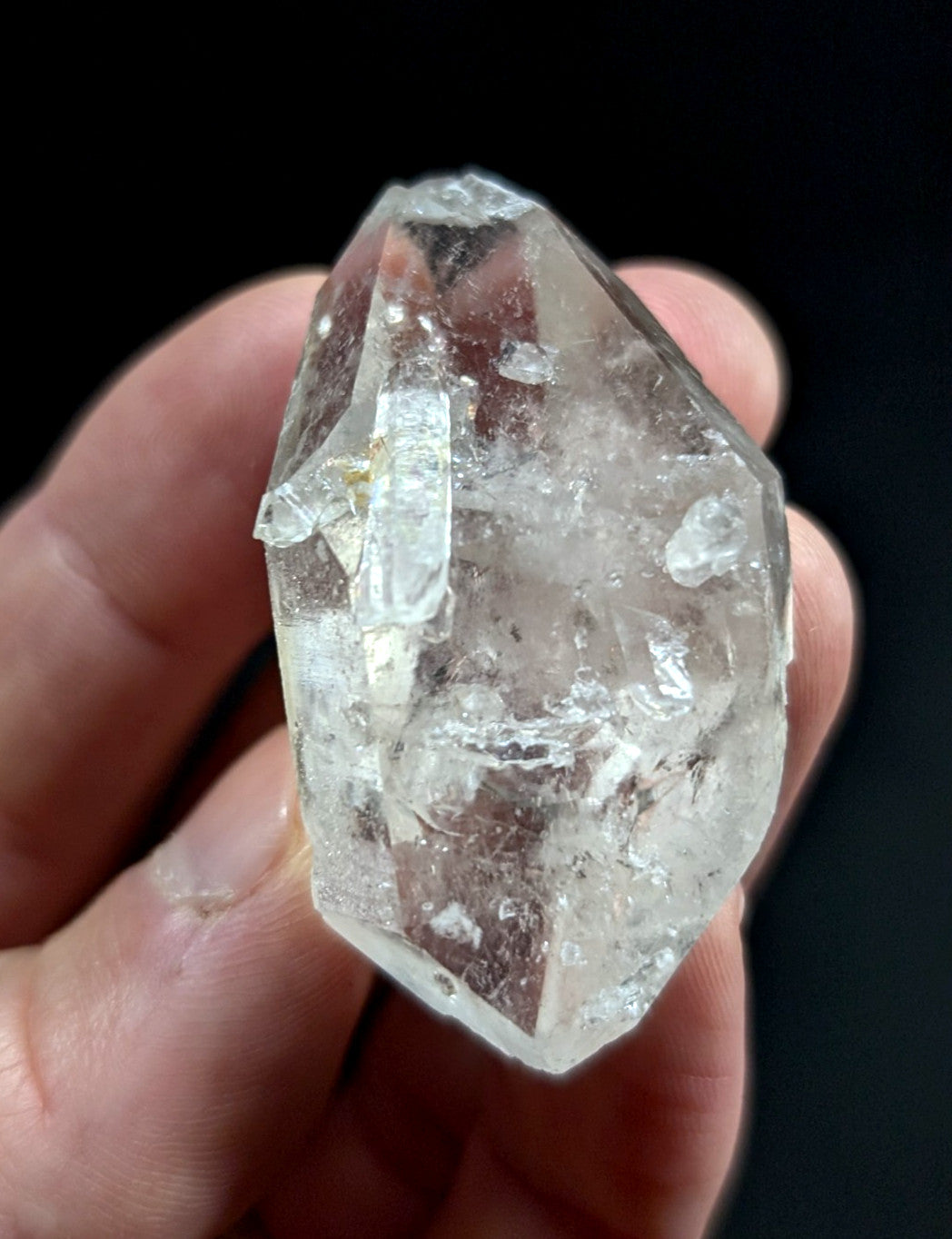 A clear, faceted quartz crystal with natural inclusions and a pointed tip.