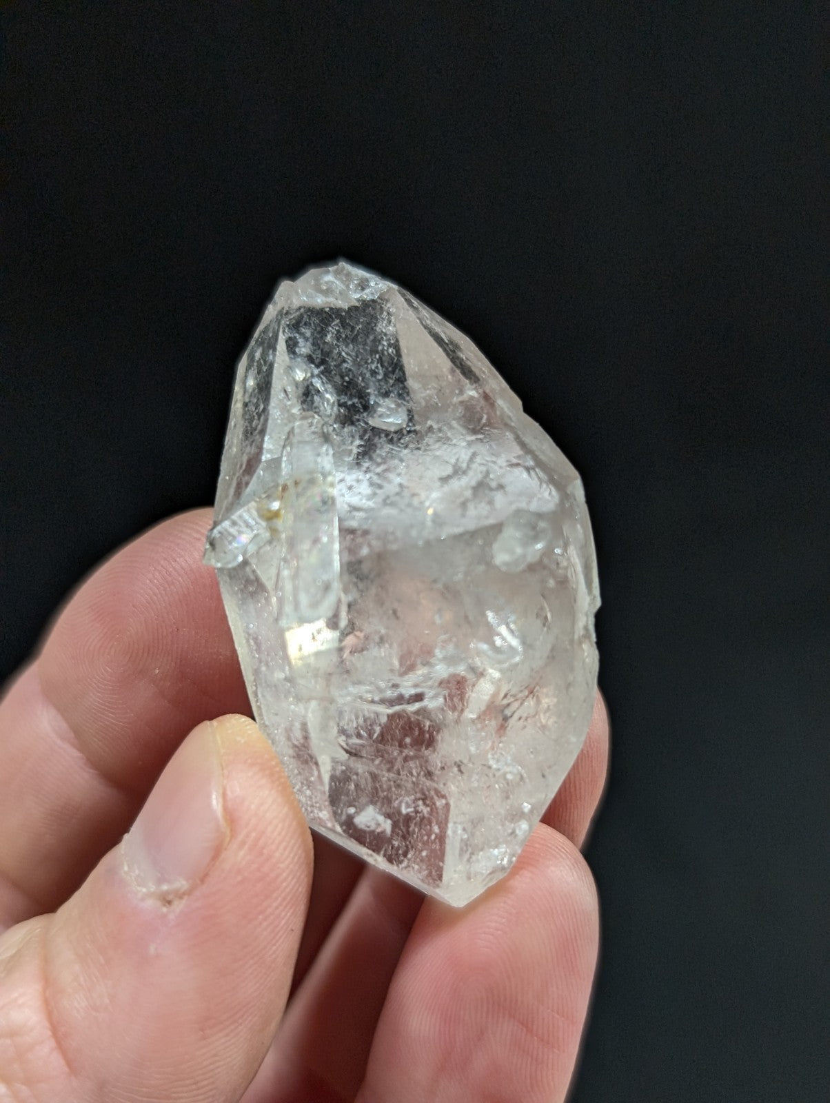 A clear, faceted quartz crystal with natural inclusions and a rough, pointed shape.