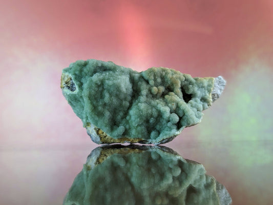 A textured, mossy green mineral specimen with a rough, crystalline surface and subtle golden accents.