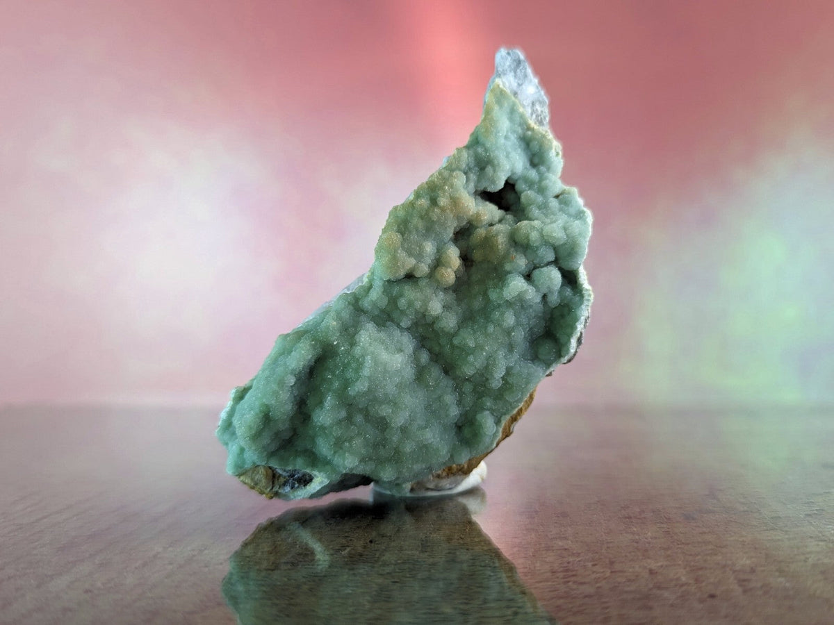 A striking greenish-blue mineral specimen with a textured, crystalline surface and hints of white and brown at its base.