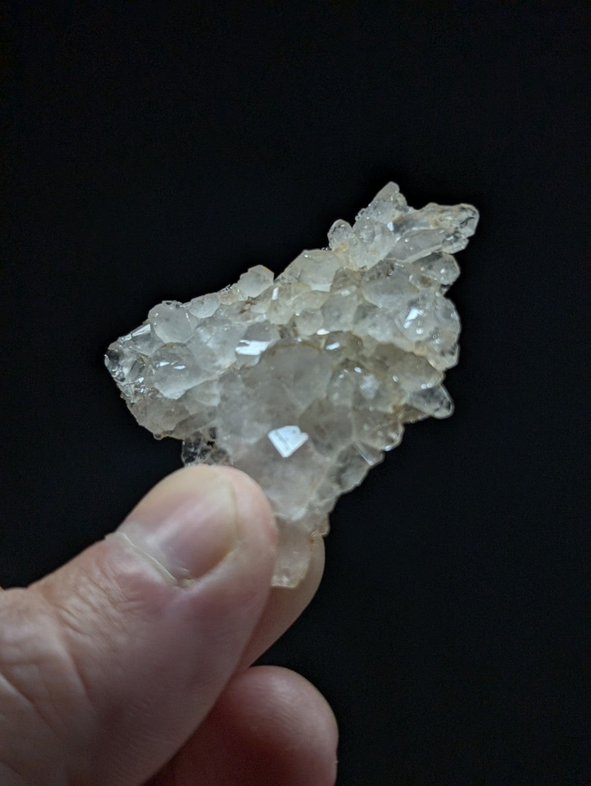 A translucent, crystalline mineral cluster with sharp facets and a pale, glassy sheen.