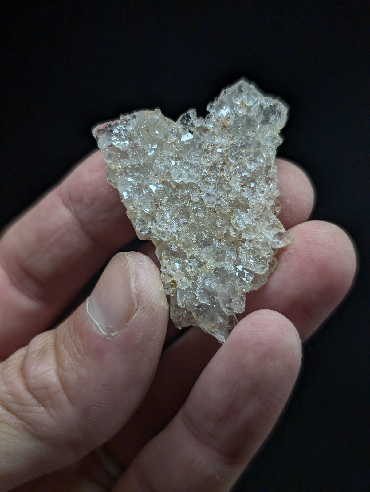 A translucent, crystalline quartz geode fragment with a rough, jagged surface and embedded clear crystals.