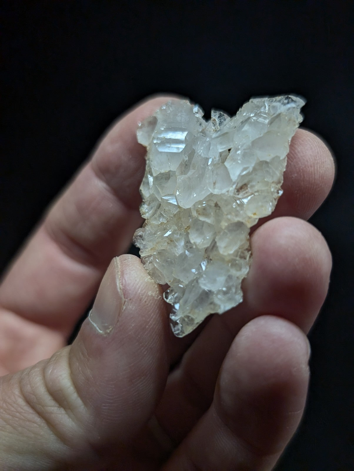A translucent, crystalline mineral specimen with a cluster of interlocking facets and subtle golden-yellow tint.
