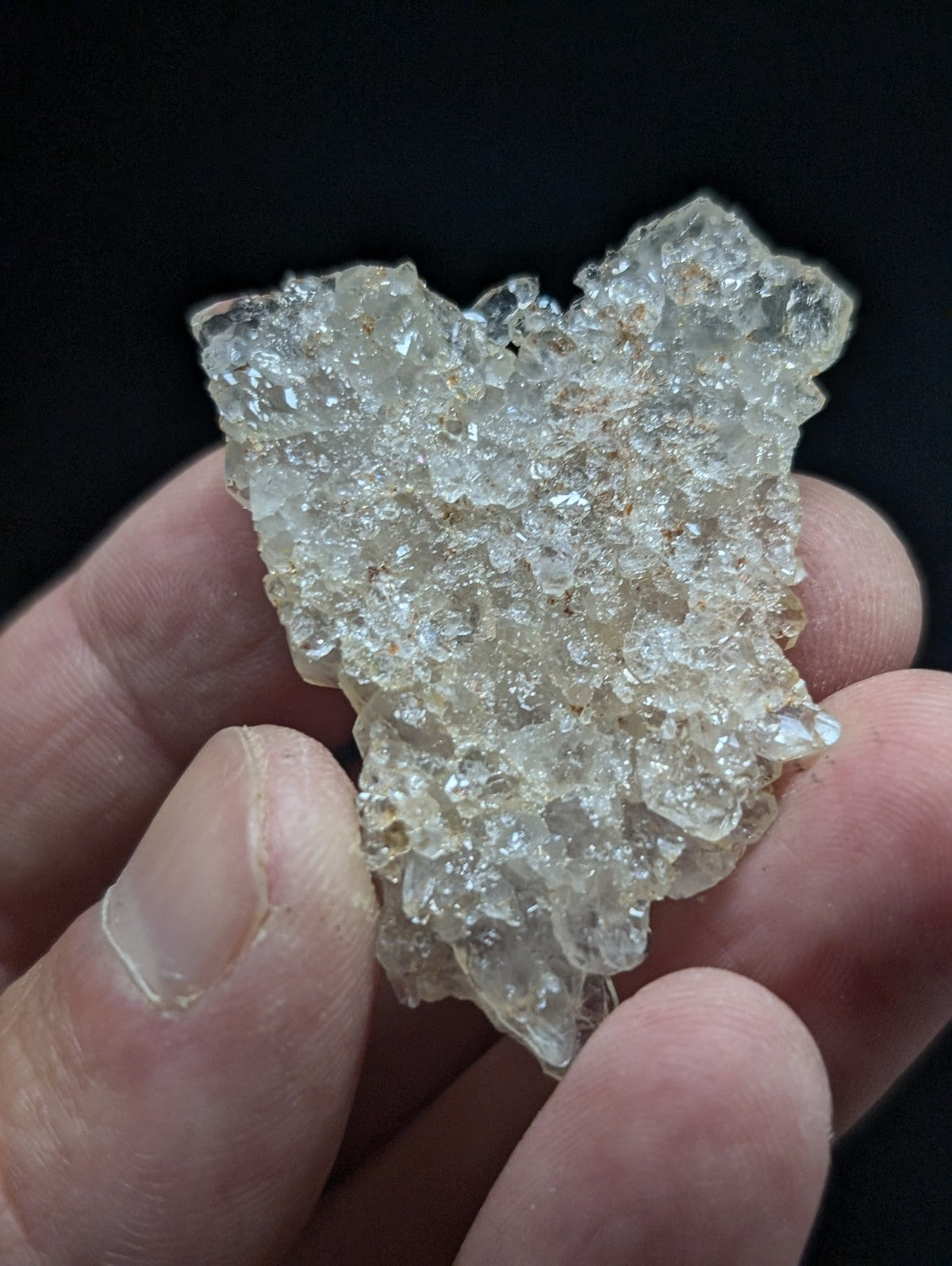 A translucent, crystalline quartz geode fragment with a rough, jagged surface and subtle golden inclusions.