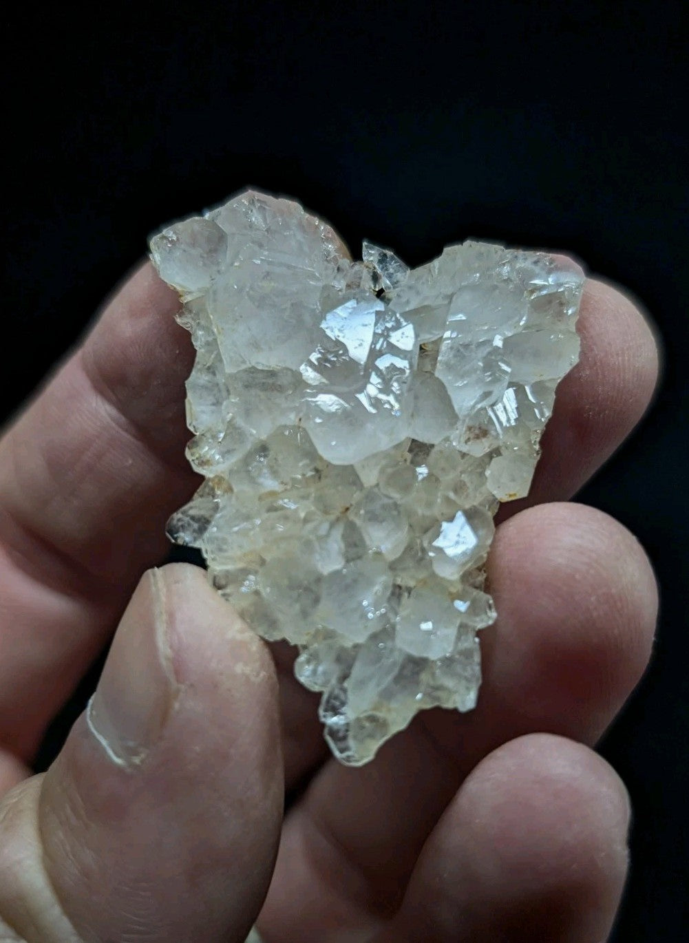 A translucent, crystalline mineral cluster with sharp facets and a pale, slightly yellowish hue.