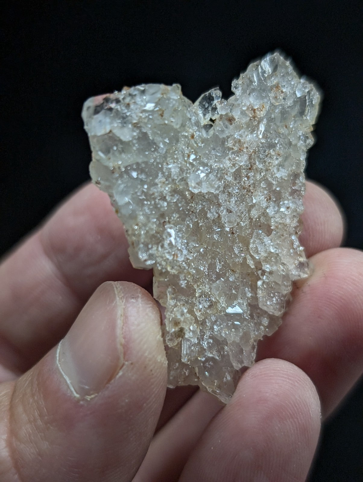 A translucent, crystalline mineral specimen with a rough, jagged surface and subtle brownish inclusions.