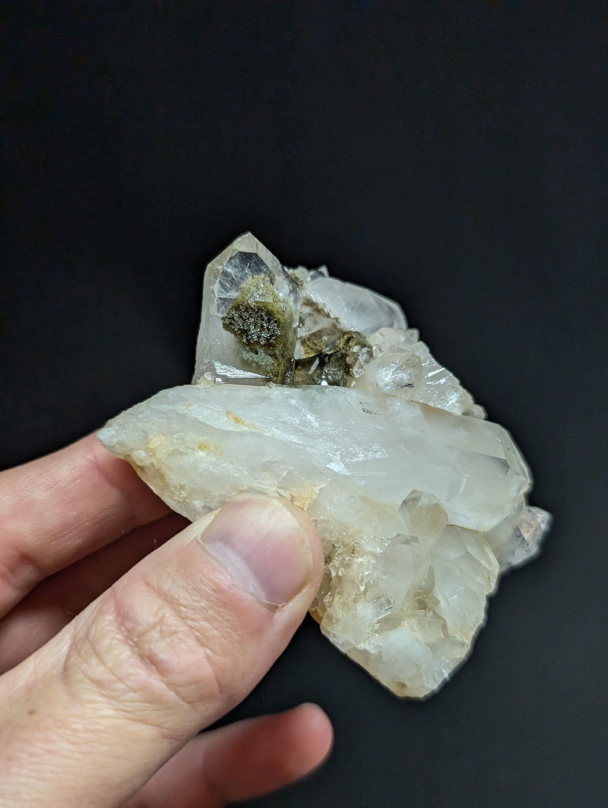 A translucent white quartz crystal cluster with greenish mineral inclusions.