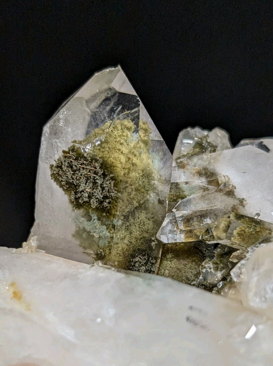 A translucent quartz crystal cluster with greenish-yellow mineral inclusions.