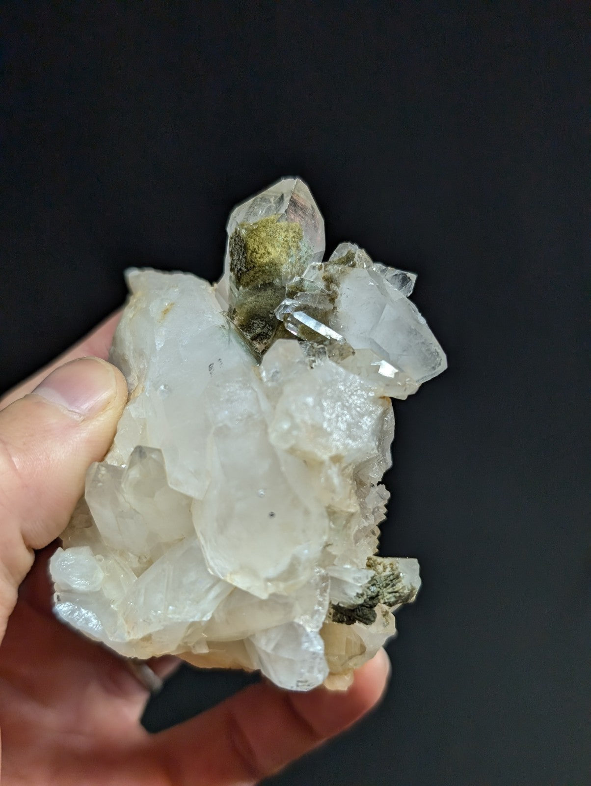 A translucent white quartz crystal cluster with clear, faceted points and patches of greenish mineral growth.