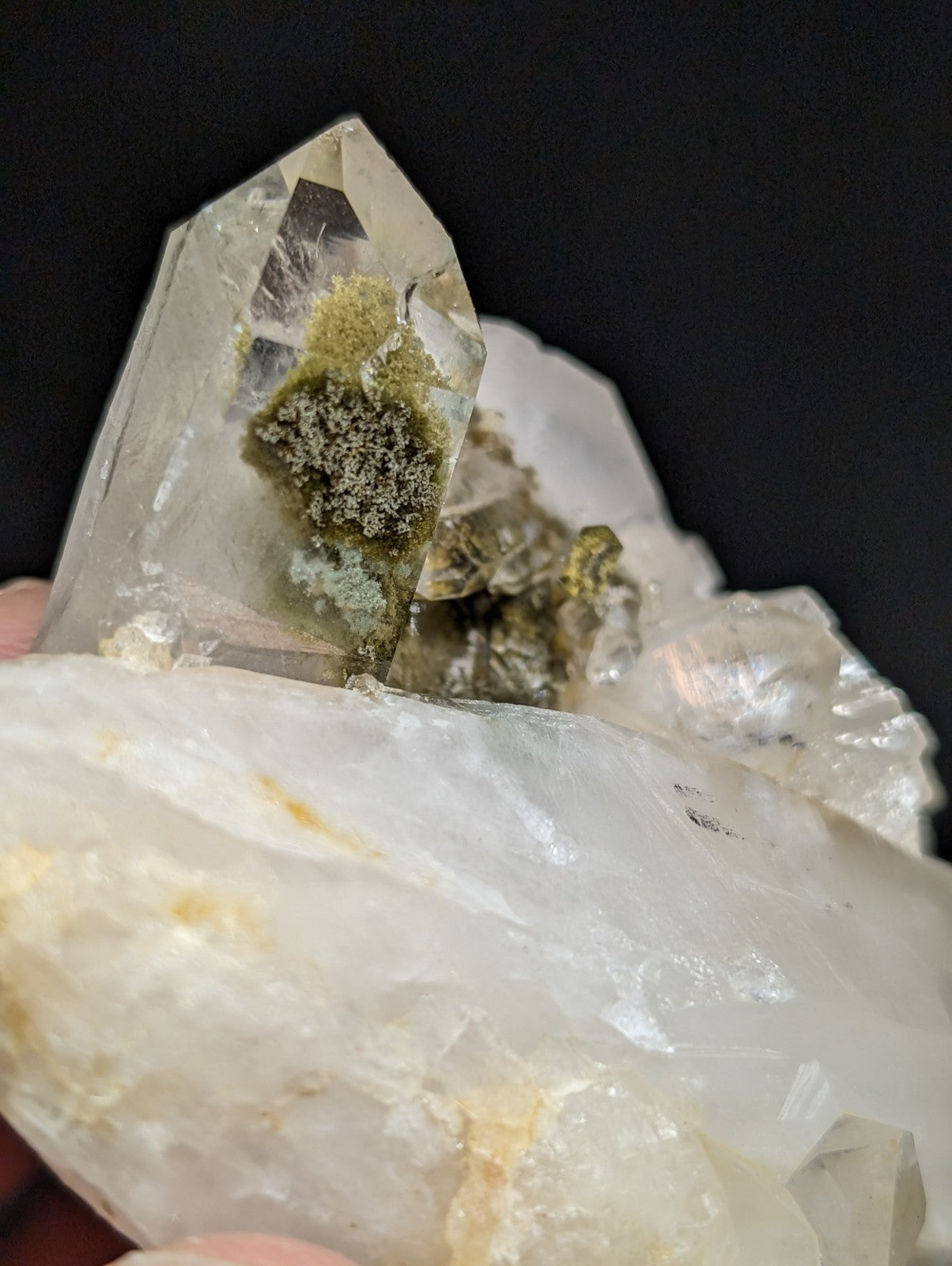 A translucent quartz crystal cluster with a prominent, clear point and embedded greenish moss-like inclusions.