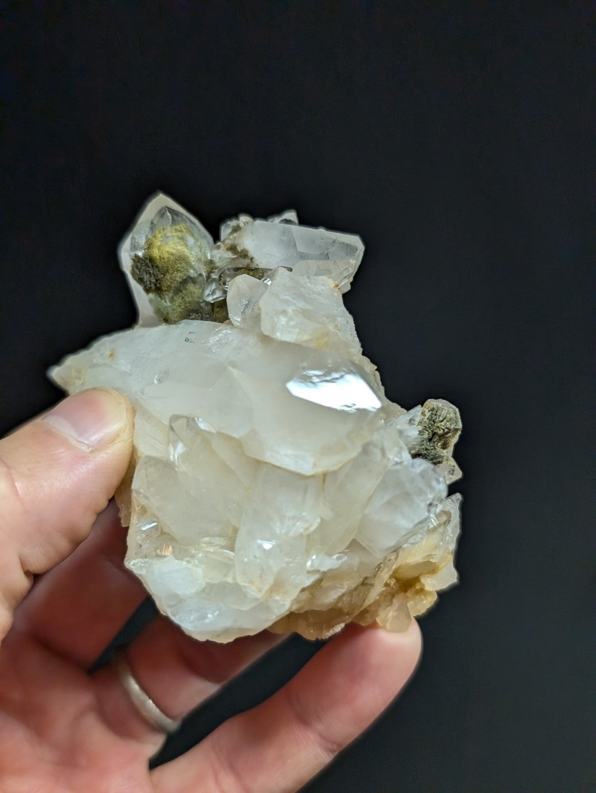 A translucent white quartz crystal cluster with some greenish and brownish mineral inclusions.