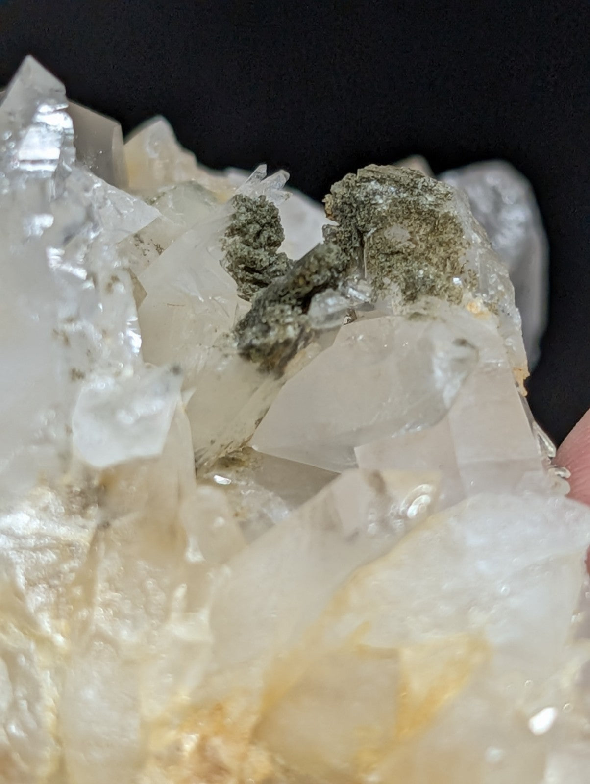 A translucent white quartz crystal cluster with a greenish mineral formation nestled among its facets.