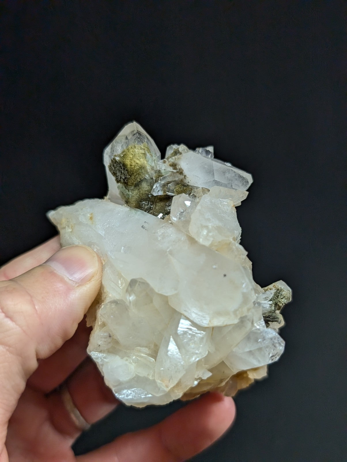 A translucent white quartz crystal cluster with some greenish mineral inclusions.