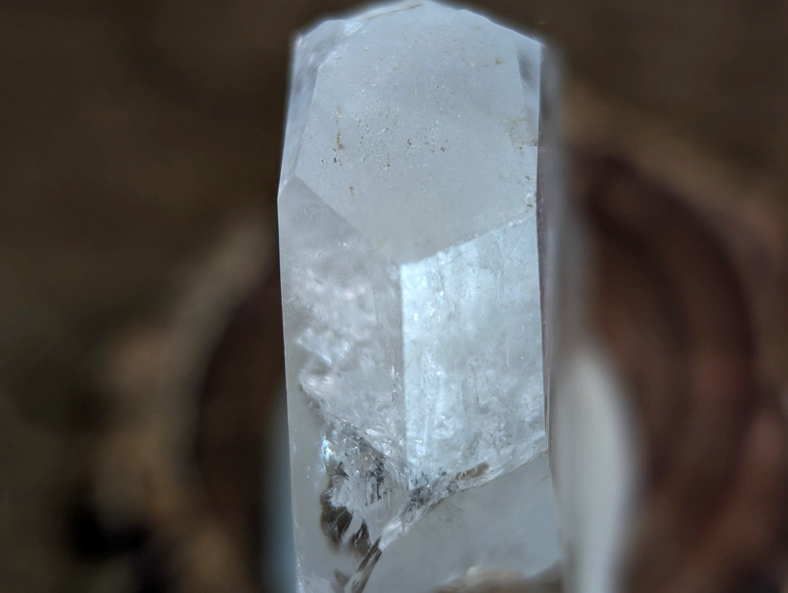 A translucent, clear quartz crystal with a faceted top and natural internal inclusions.