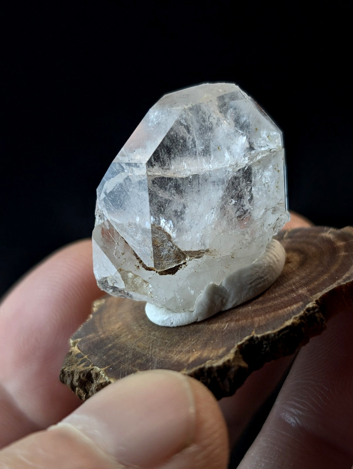 A clear, faceted quartz crystal with natural inclusions and a polished base.