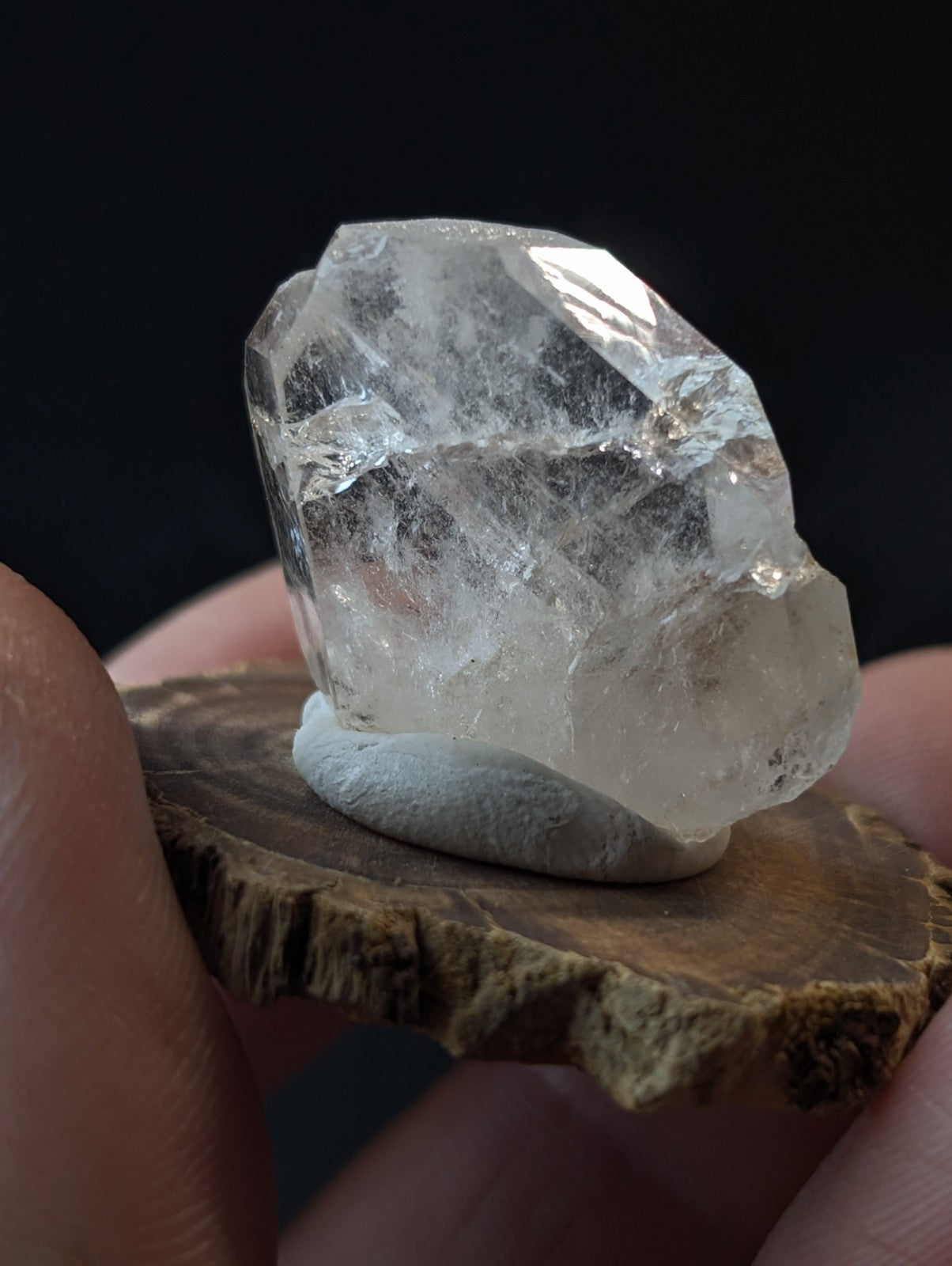 A clear, faceted quartz crystal with natural inclusions and a smooth base.