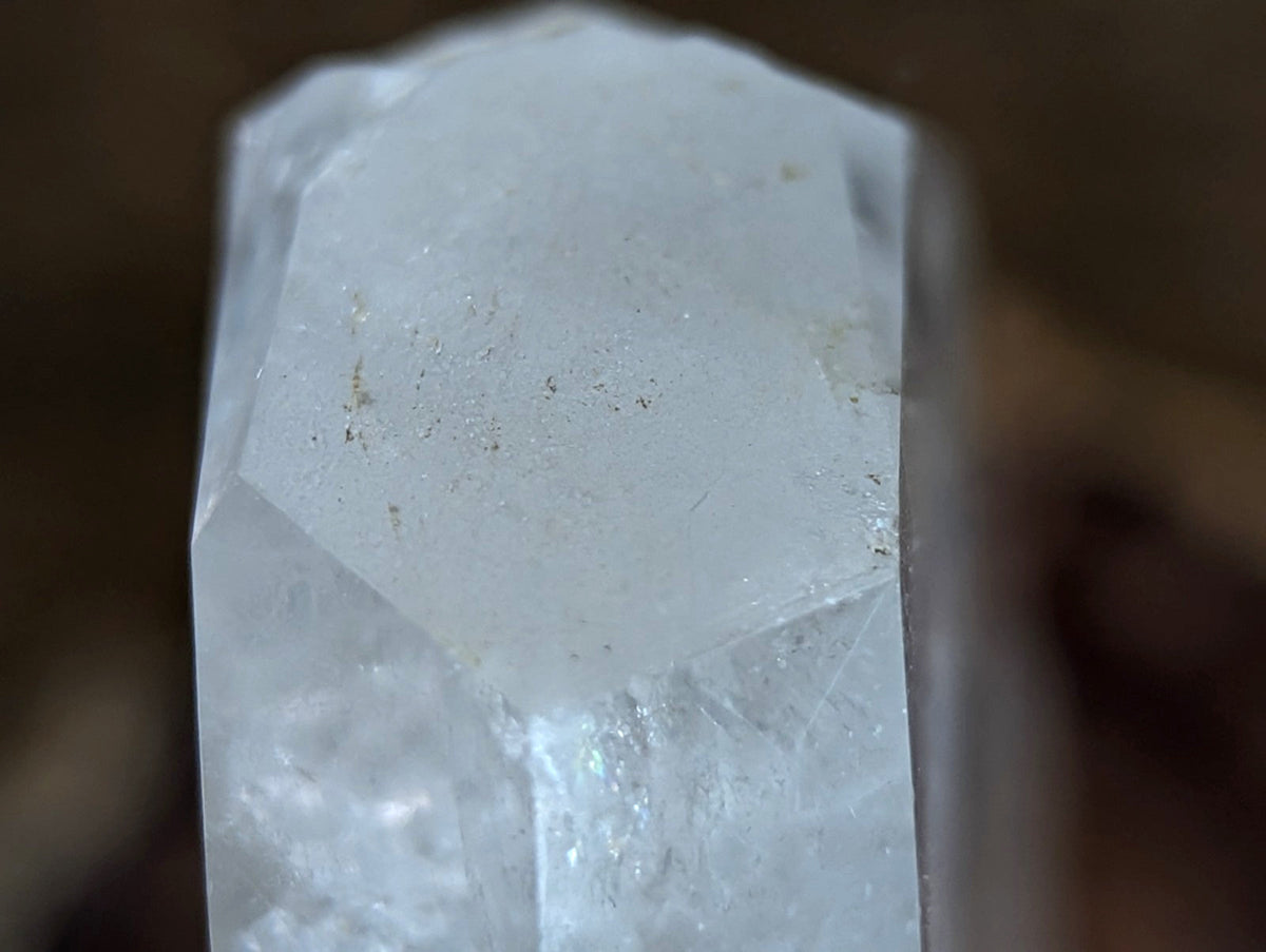 A translucent, pale white quartz crystal with a faceted top and natural inclusions.