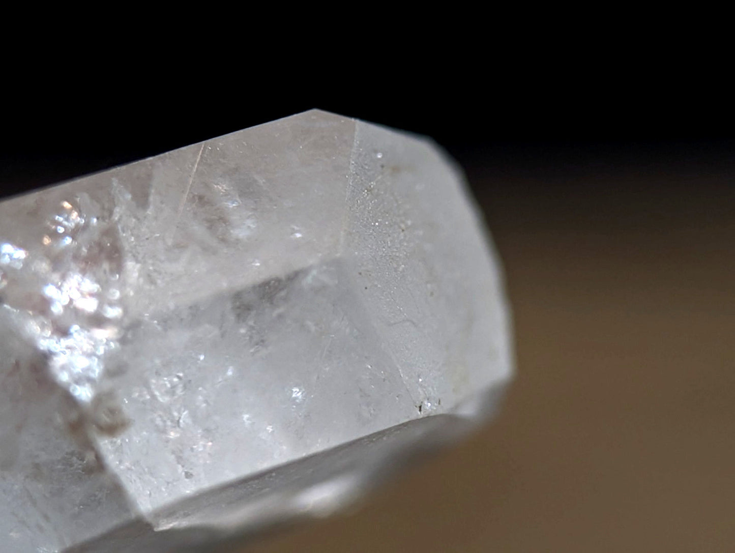 A translucent, clear quartz crystal with a faceted cut and visible internal inclusions.