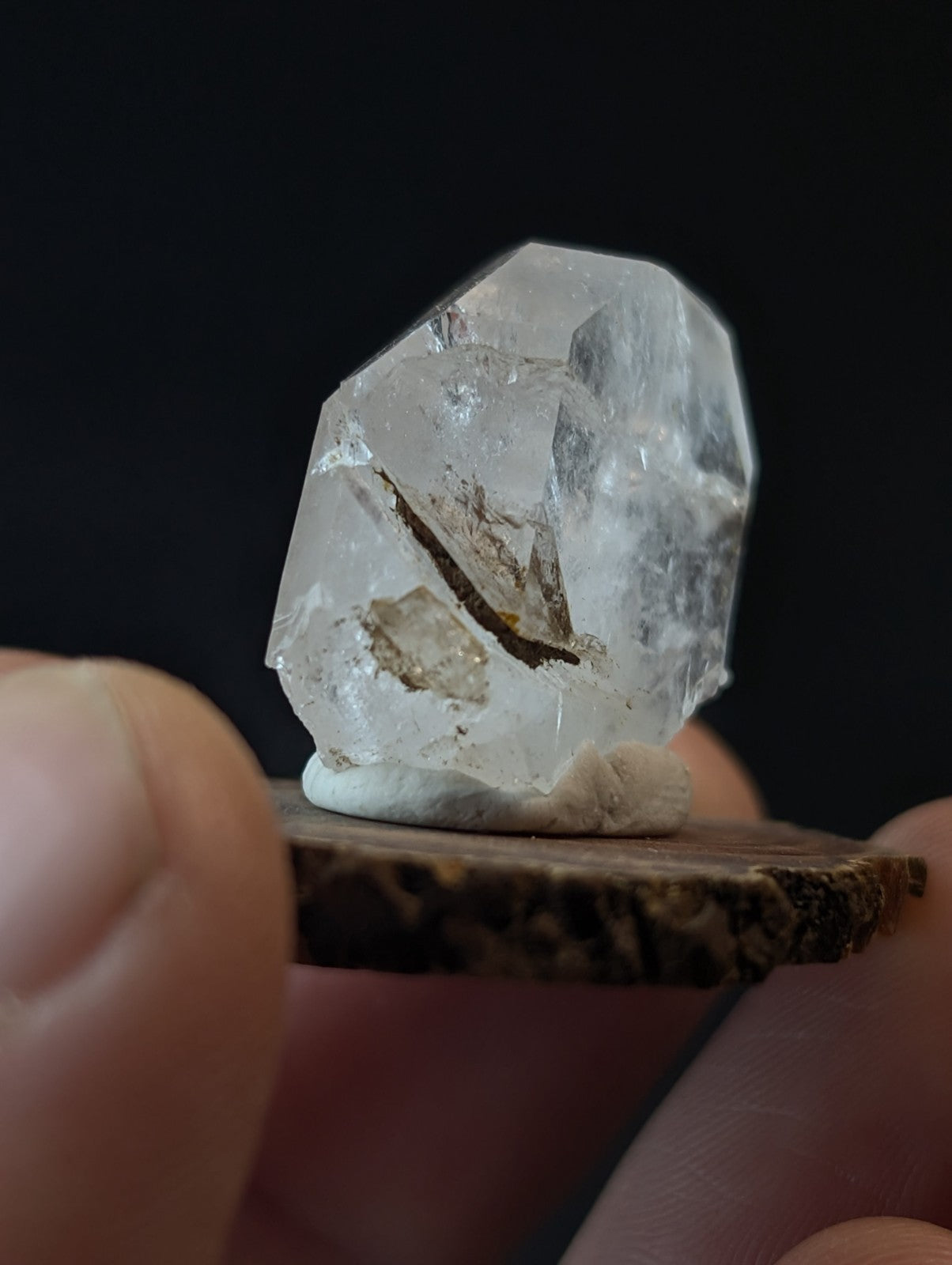 A clear, faceted quartz crystal with natural inclusions and a rough-edged base.