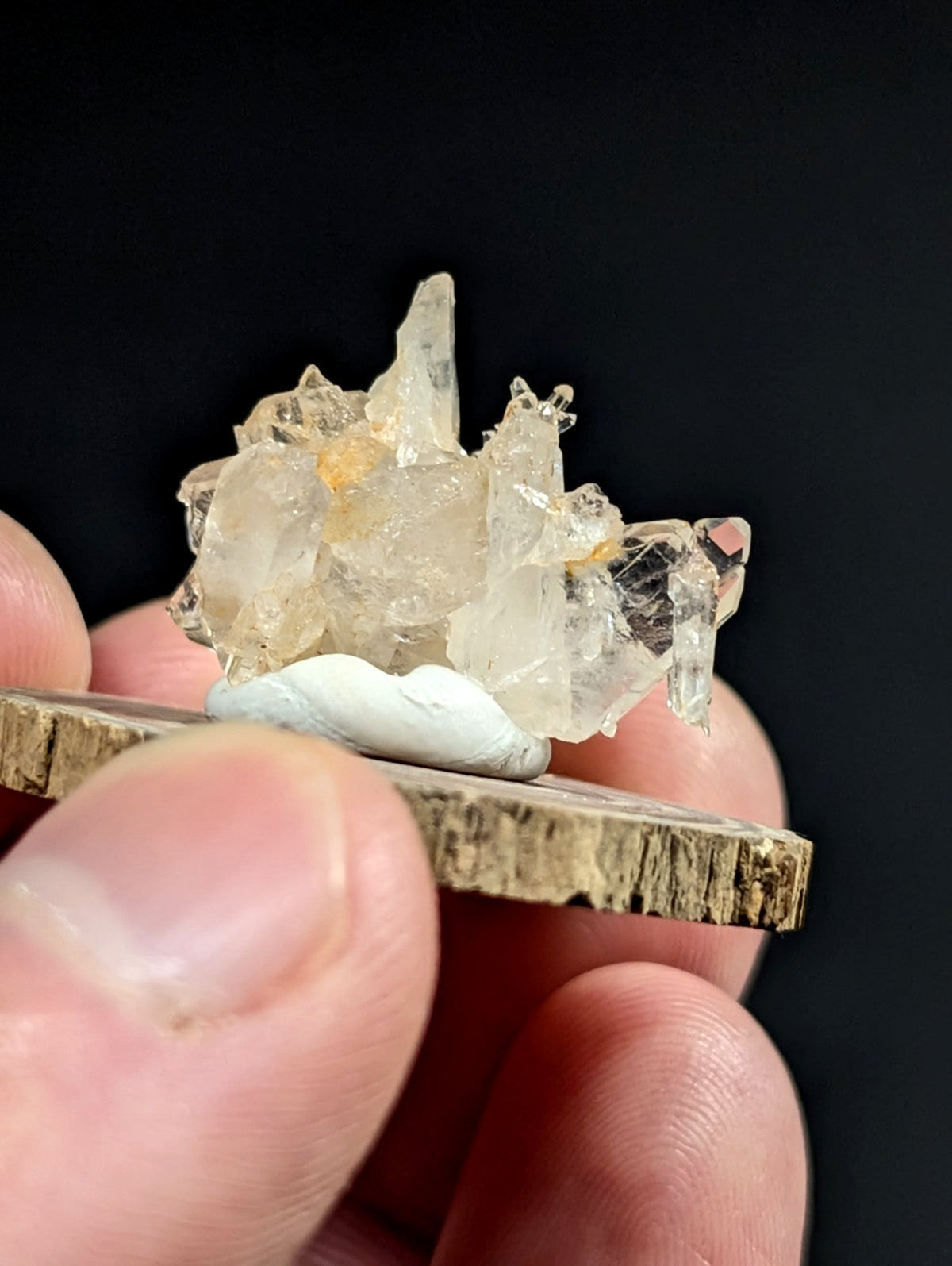 Faden quartz crystal cluster with amber inclusions and sharp facets on a rustic wooden base from Arkansas