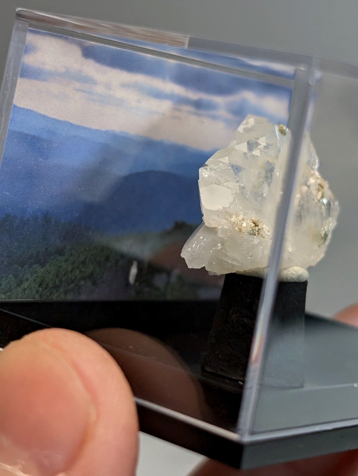 A clear faceted faden quartz crystal with subtle golden inclusions in a transparent acrylic display case from saline county arkansas