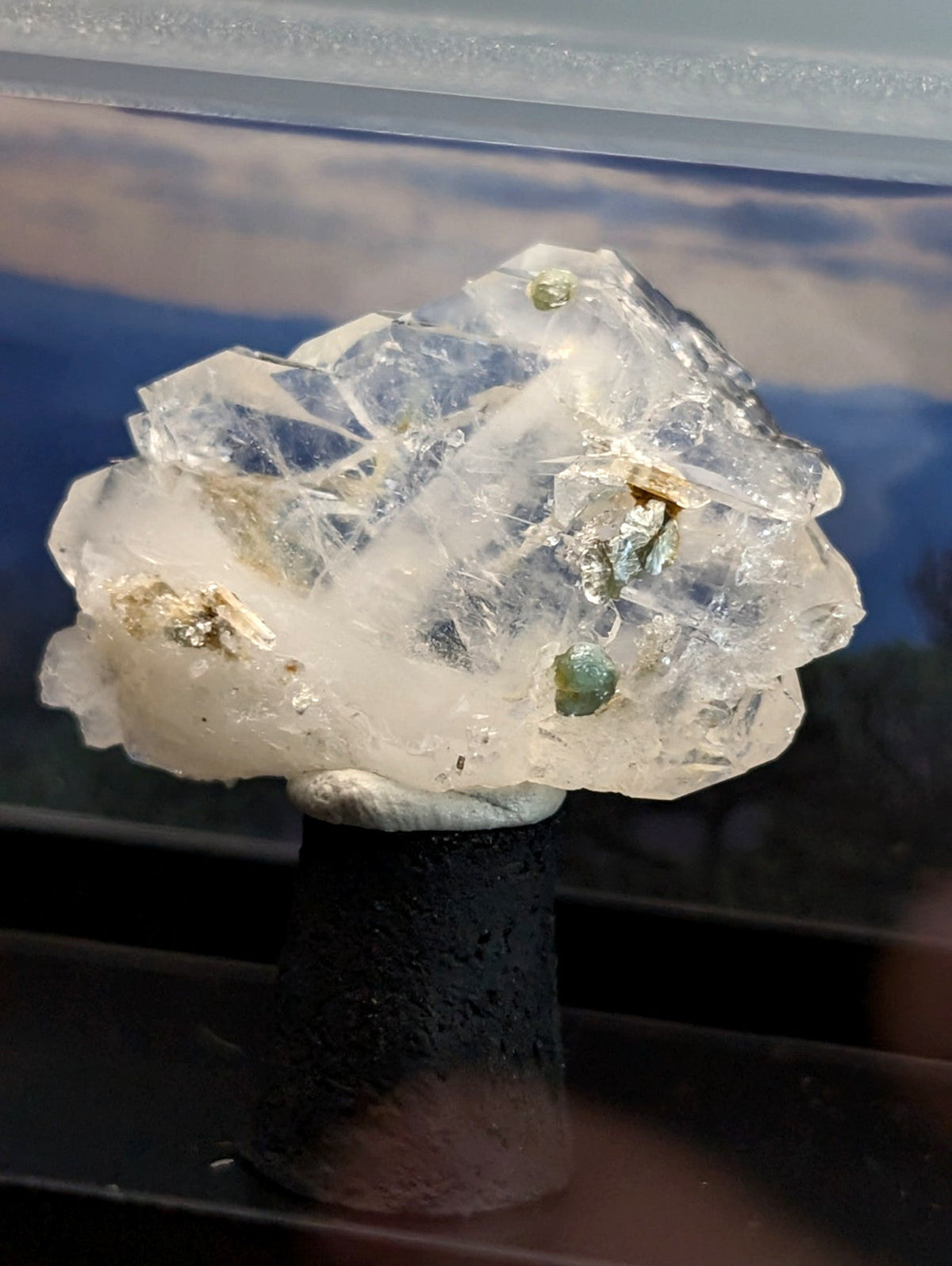 Faden quartz crystal cluster with green and golden mineral inclusions on dark stand from saline county arkansas