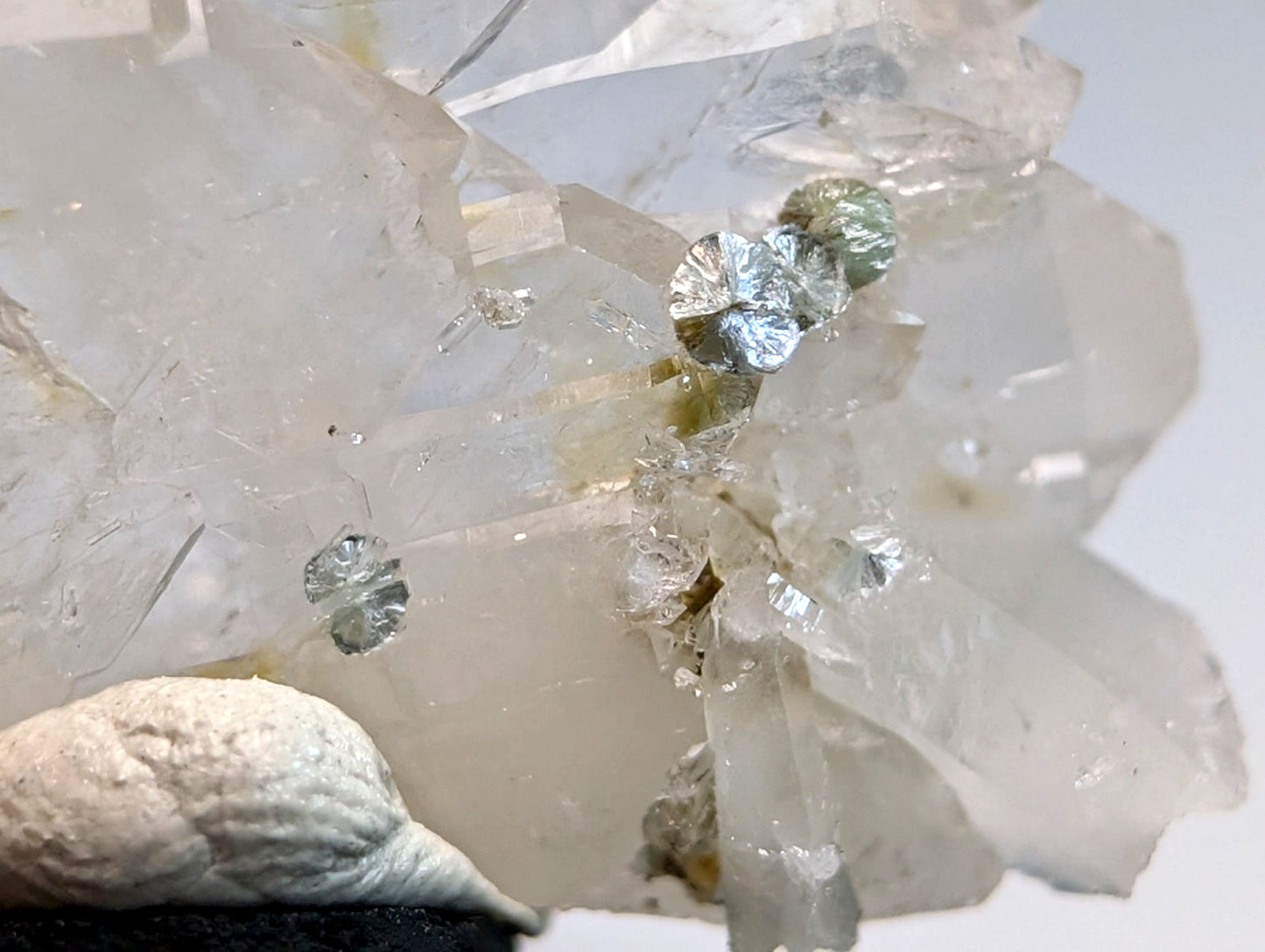 A cluster of translucent faden quartz crystals with blue-green uv reactive cookeite and metallic leaf inclusions