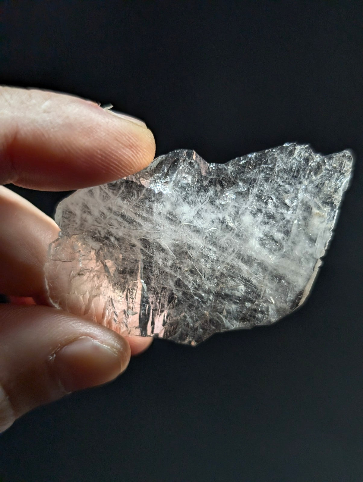 A translucent, clear quartz crystal with a rough, jagged surface and visible internal striations.