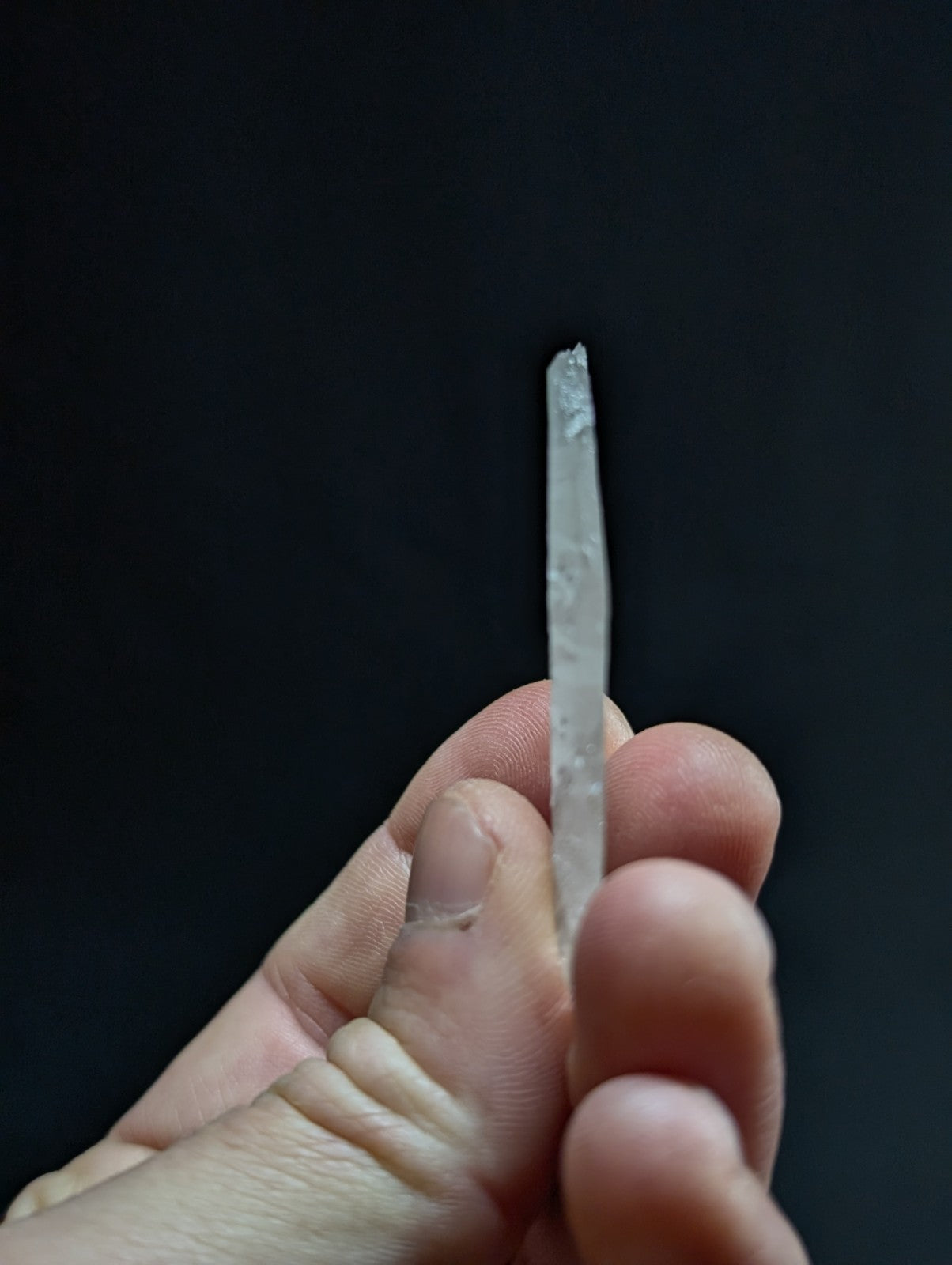 A translucent, clear quartz crystal with a pointed tip and natural facets.