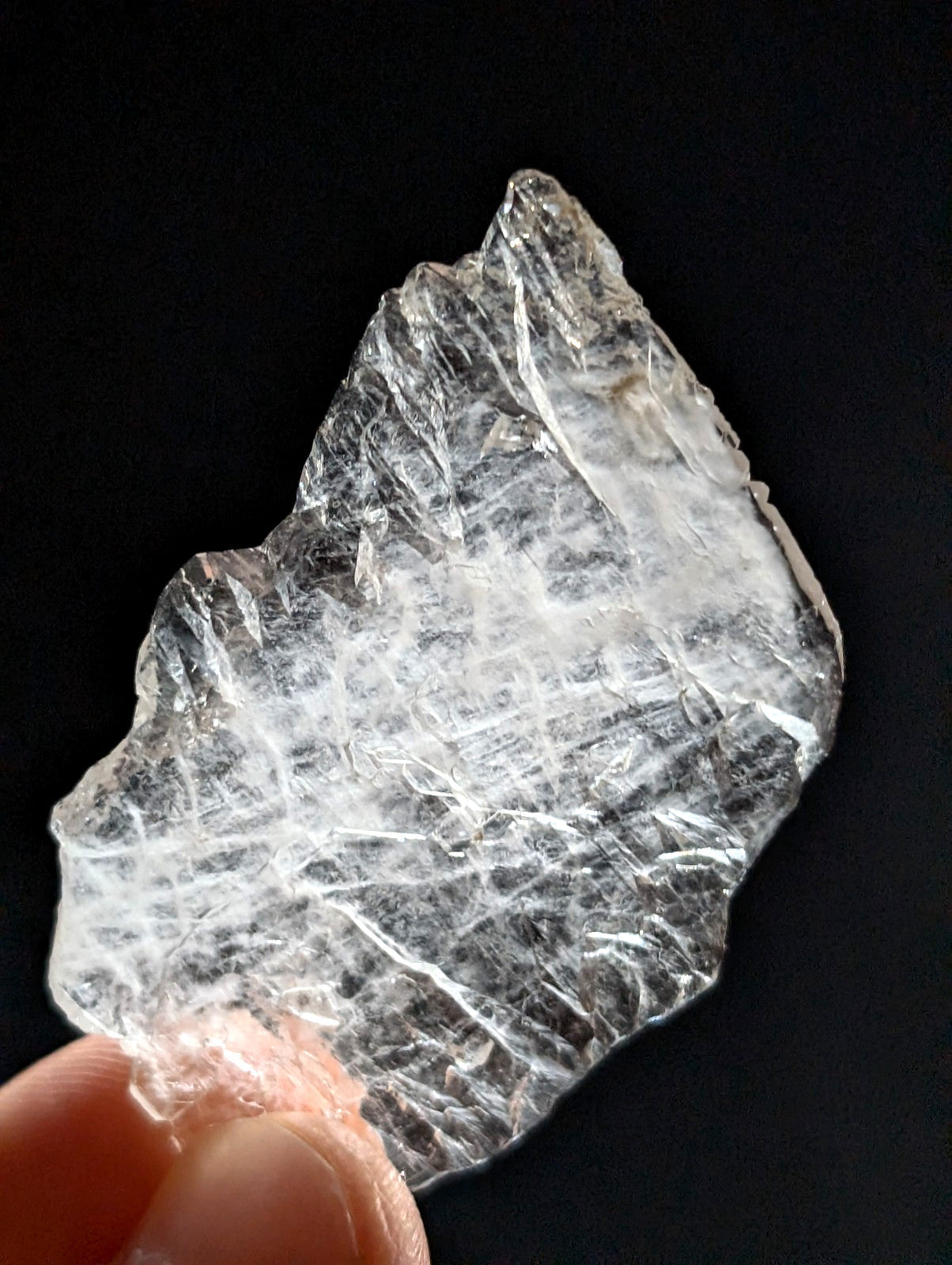 A translucent, clear quartz crystal with a rough, jagged surface and visible internal striations.