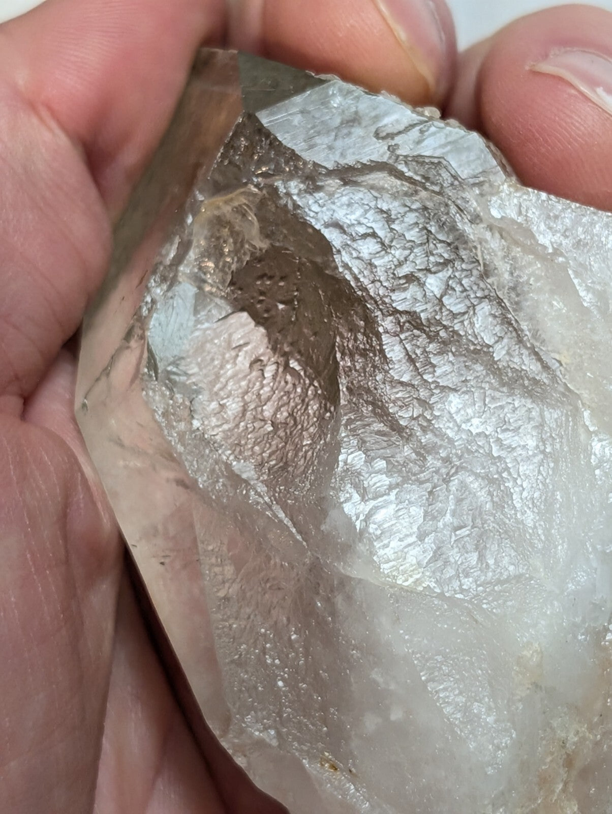 A translucent, rough-hewn quartz crystal with a metallic sheen and natural facets.