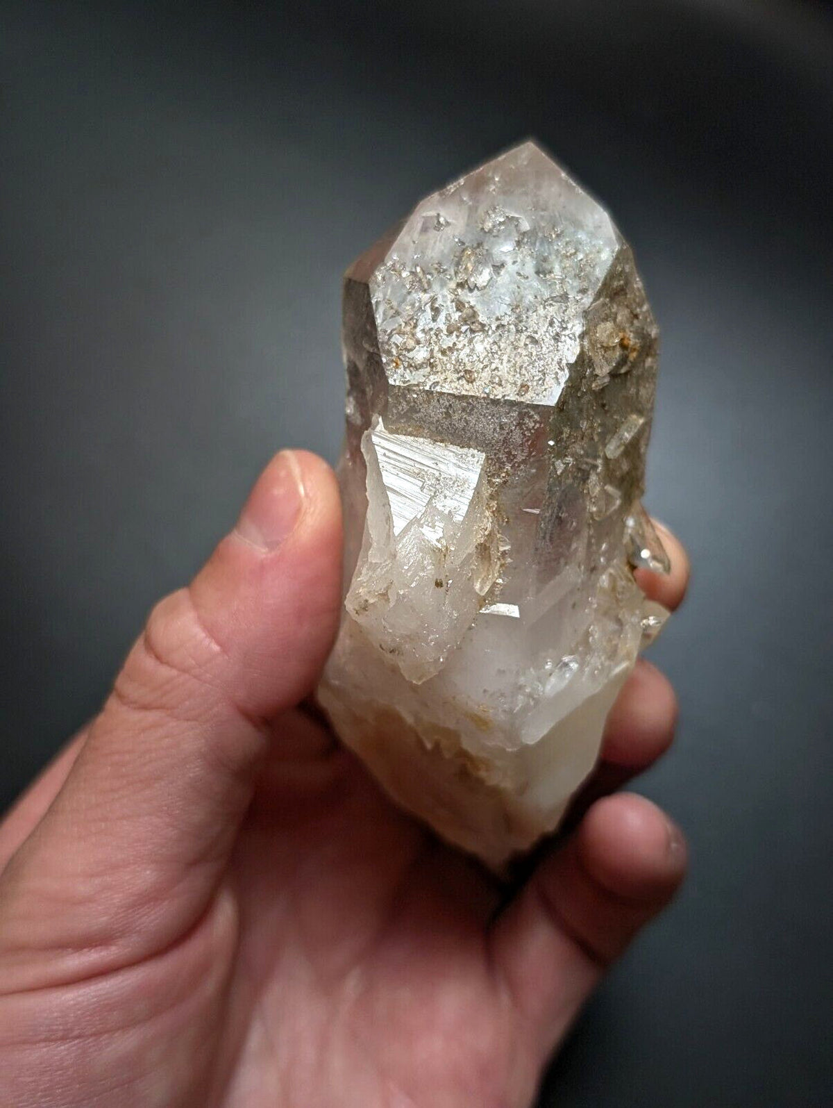 A translucent, clear quartz crystal with a pointed tip and visible internal inclusions.