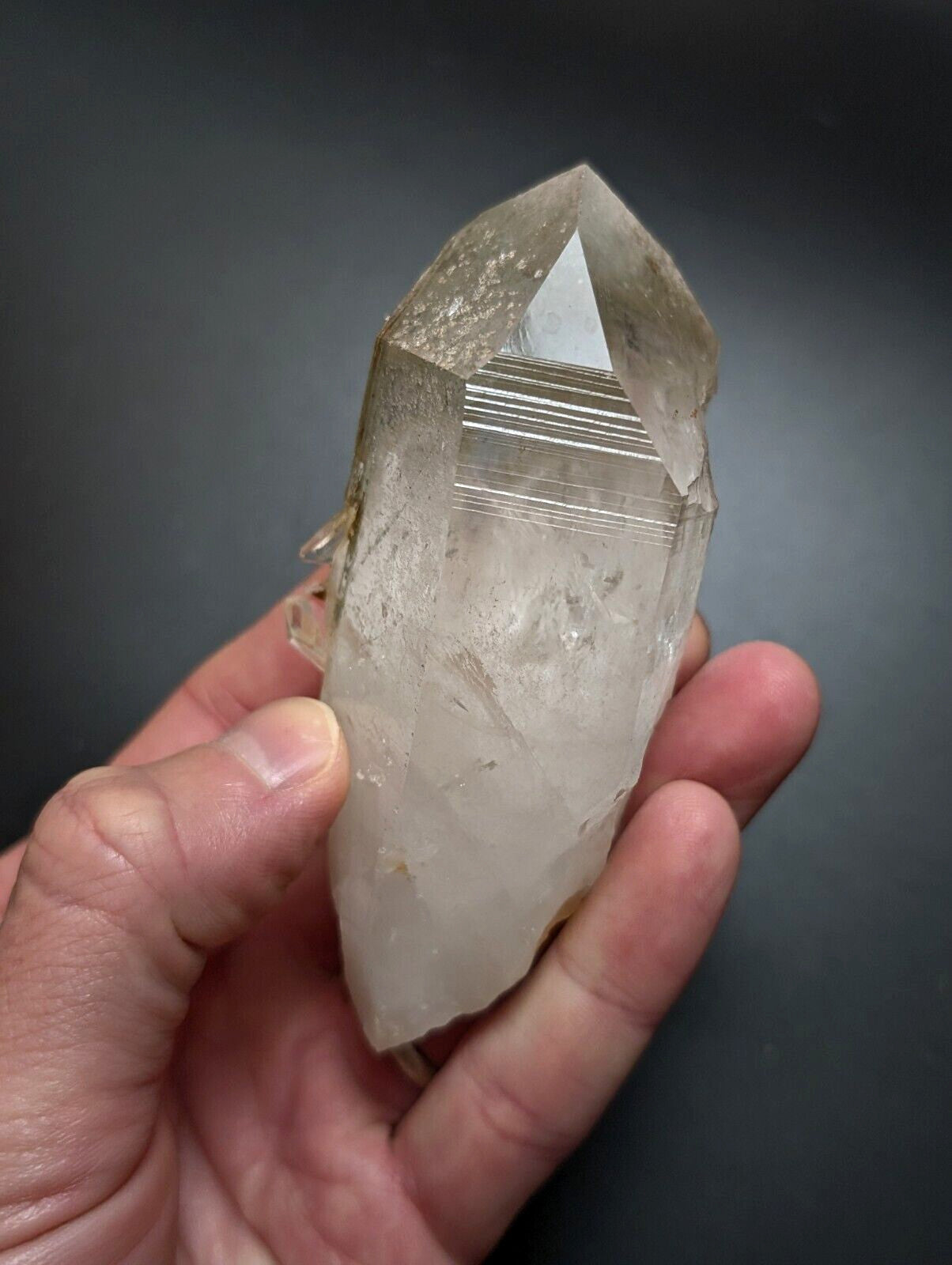 A translucent, pale quartz crystal with natural striations and a pointed tip.