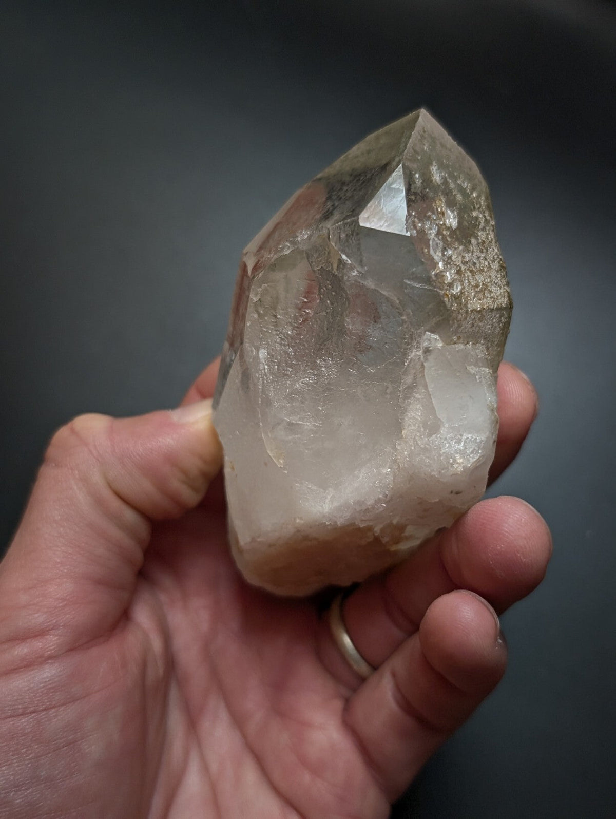 A translucent, clear quartz crystal with a pointed tip and natural inclusions.