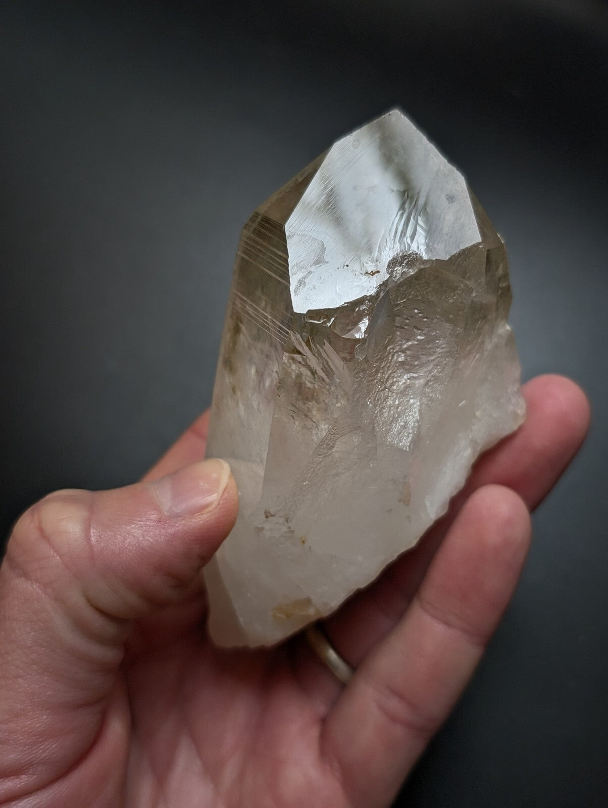 A translucent, pale yellowish quartz crystal with a pointed tip and natural striations.
