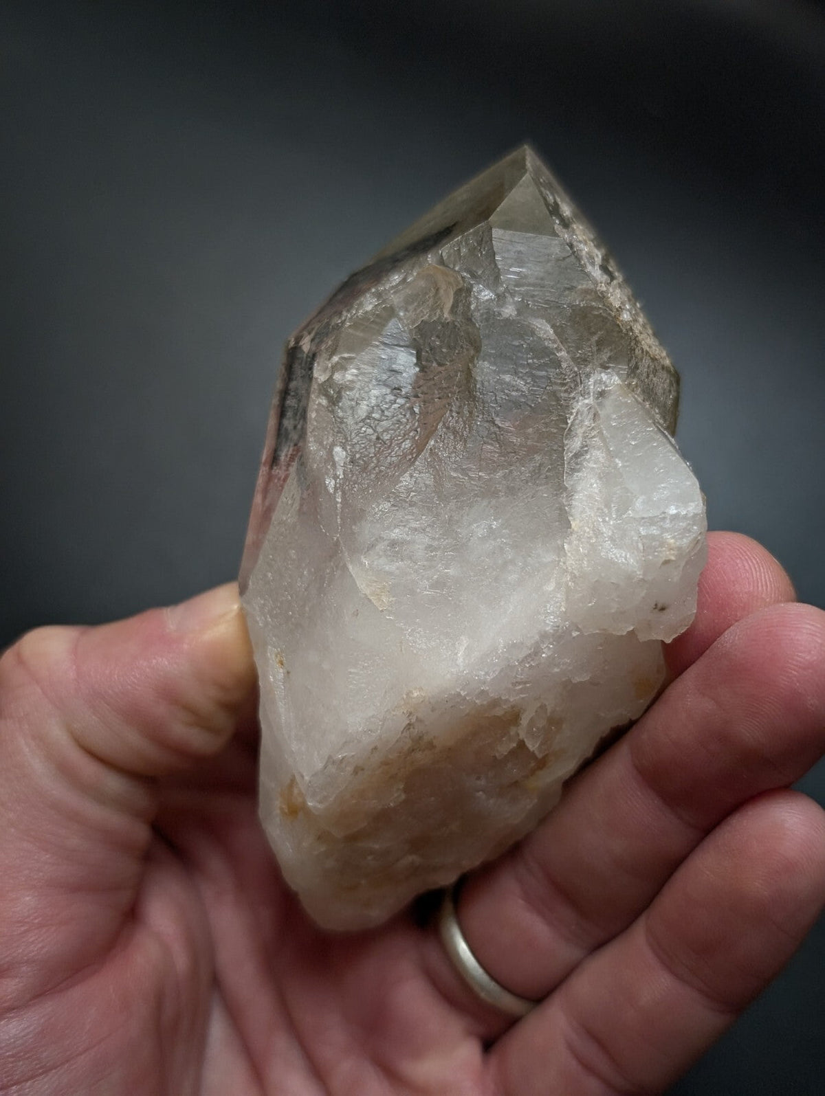 A translucent, faceted quartz crystal with a pointed tip and natural mineral inclusions.