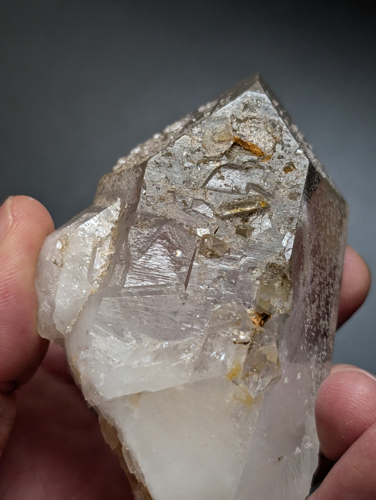 A translucent, multi-faceted quartz crystal with embedded golden inclusions and a rough, natural surface.