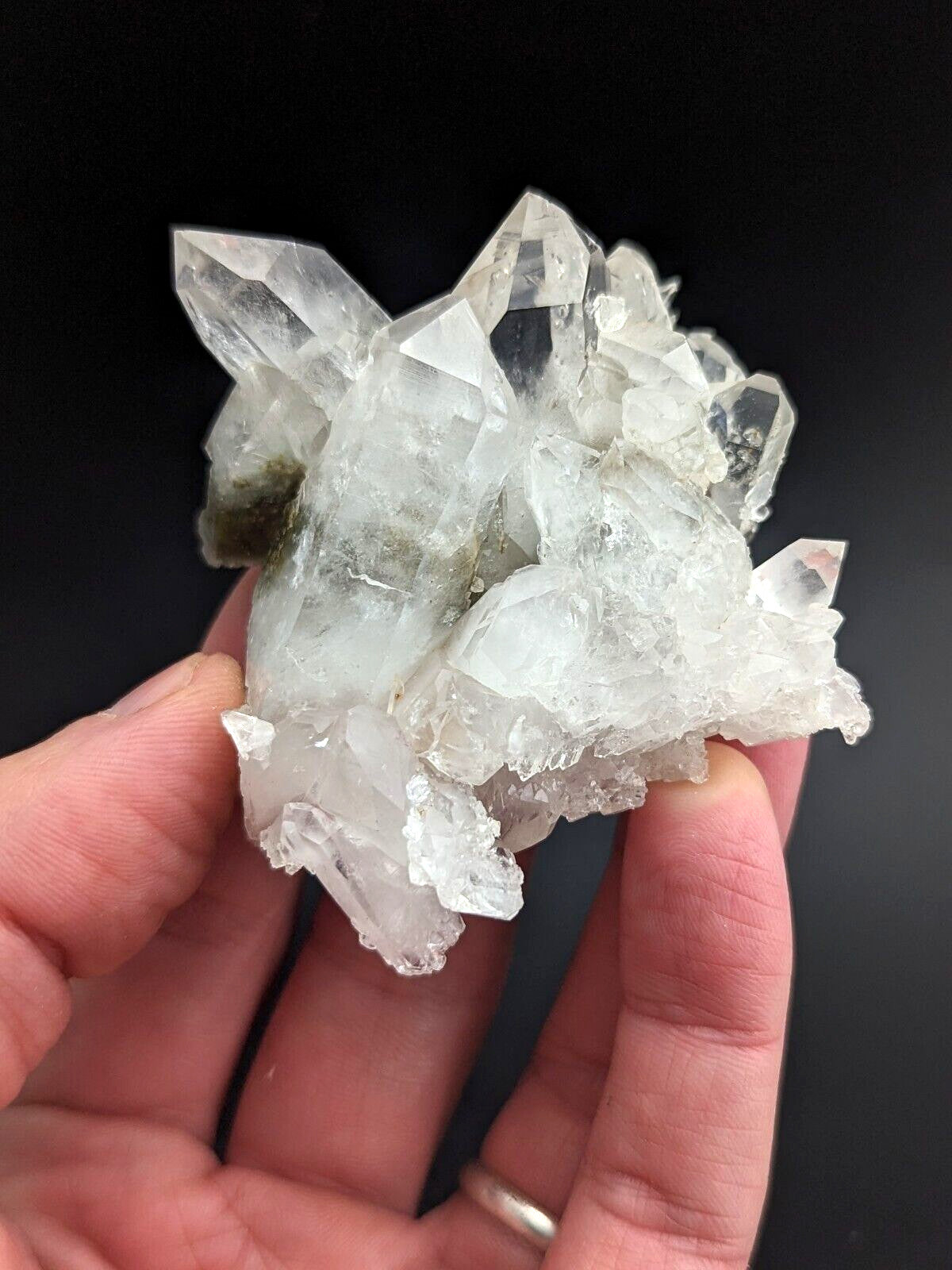 A clear, faceted quartz crystal cluster with a natural, jagged formation and subtle greenish inclusions.