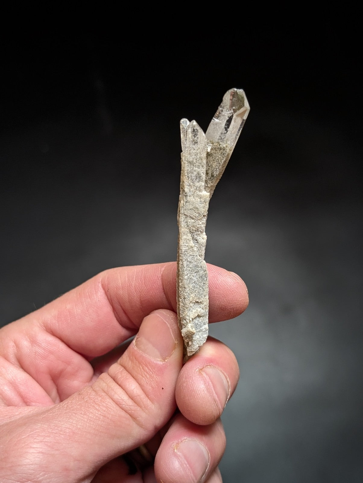 A translucent, pale quartz crystal cluster with a rough-textured base and pointed, faceted tips.