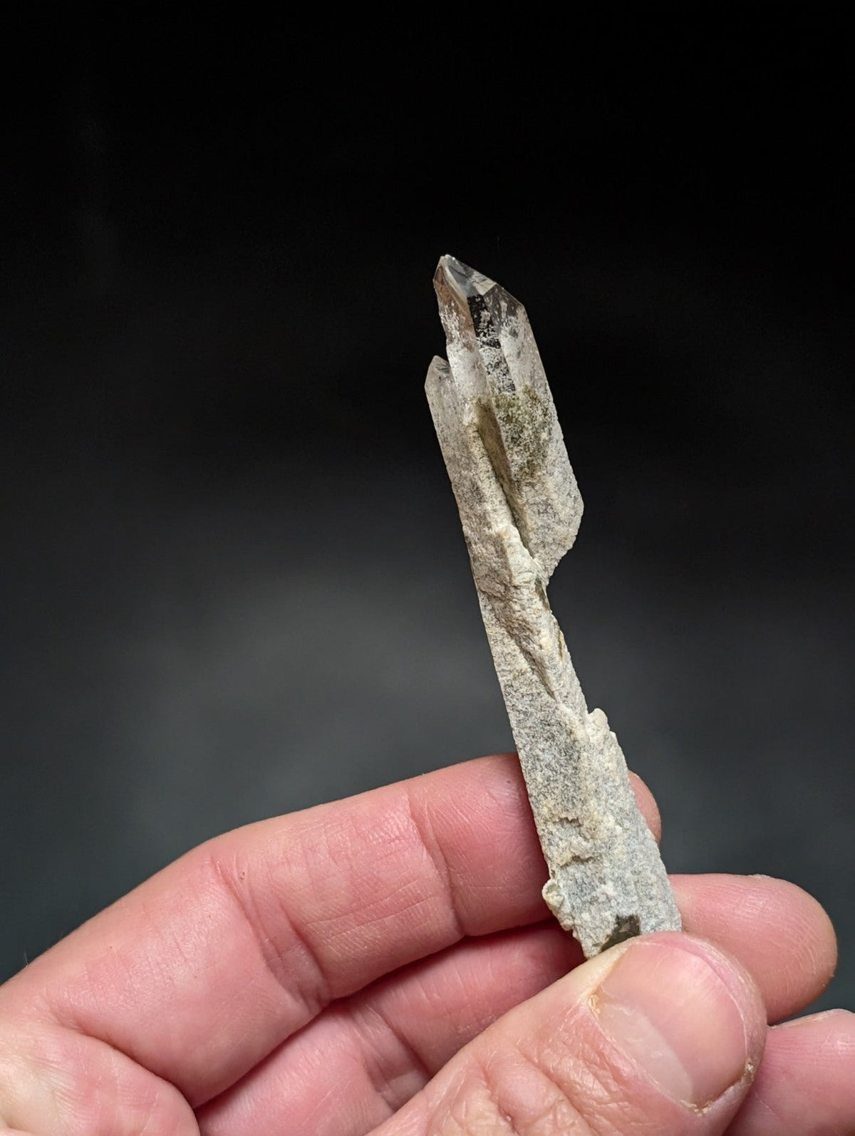 A translucent, pale gray quartz crystal with a pointed tip and natural striations.